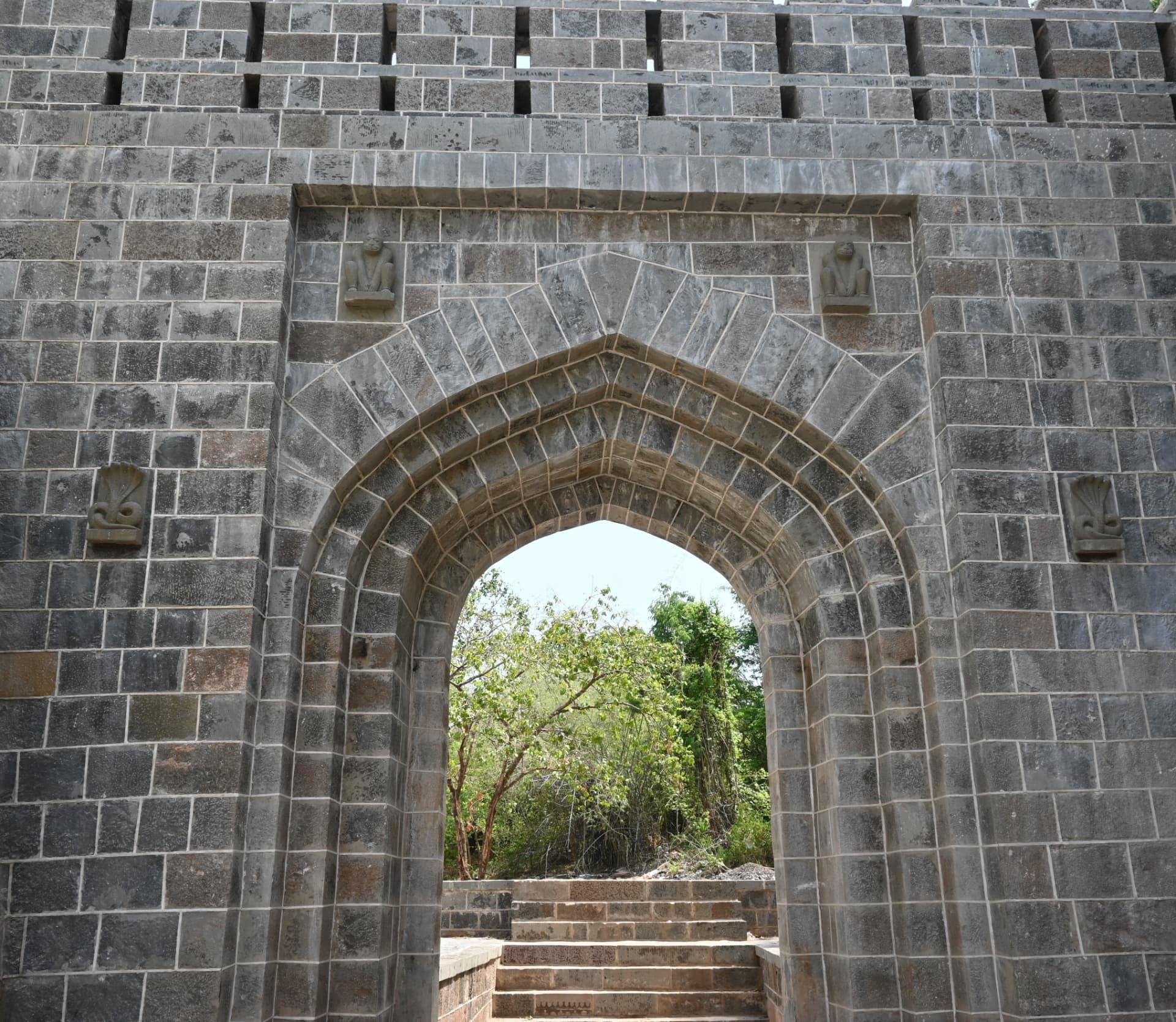 Restored arched gateway with carved figures at Manikgad Fort